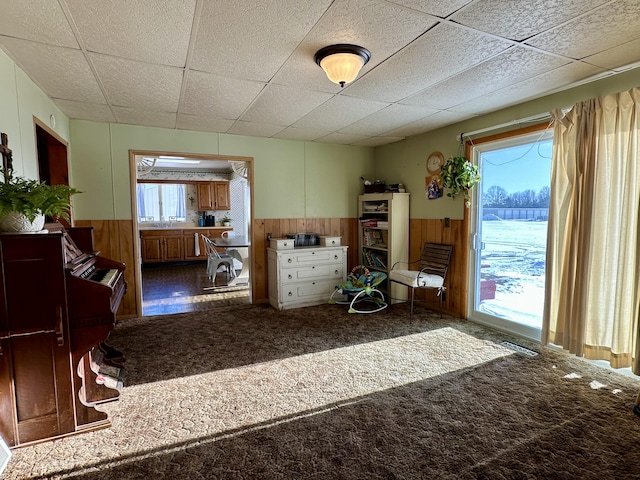 unfurnished bedroom with carpet, a paneled ceiling, and wood walls