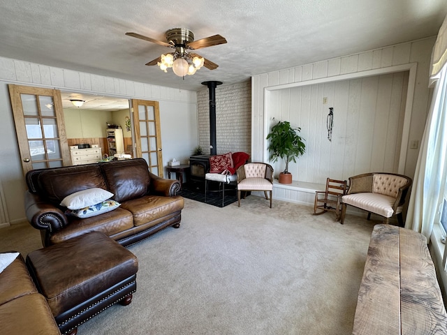 living room with carpet flooring, a wood stove, ceiling fan, and french doors