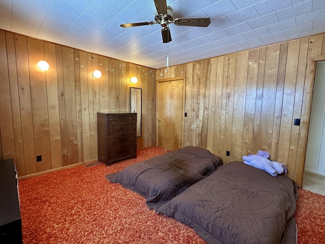 bedroom with ceiling fan, carpet floors, and wooden walls