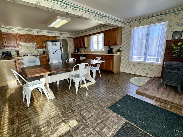 dining space featuring dark parquet floors, a wood stove, crown molding, and sink