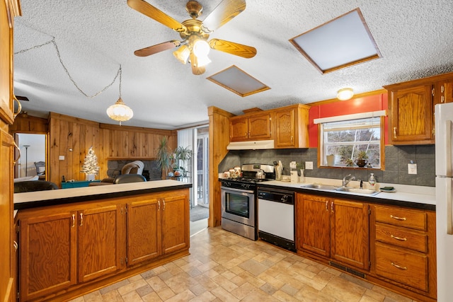 kitchen featuring wood walls, white appliances, backsplash, sink, and ceiling fan