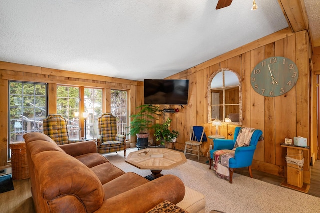 living room with wood-type flooring, a textured ceiling, ceiling fan, and wood walls