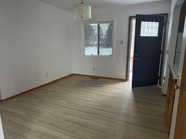 entrance foyer with hardwood / wood-style flooring, ornamental molding, and a chandelier