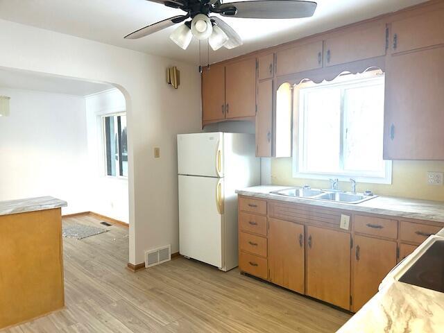 kitchen featuring ceiling fan, sink, white refrigerator, stovetop, and light wood-type flooring