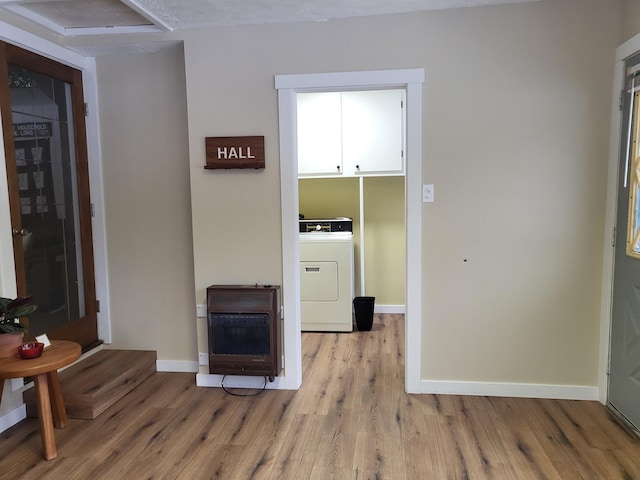 interior space with light wood-type flooring, a textured ceiling, washer / clothes dryer, and heating unit