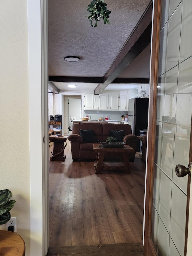 hall featuring beamed ceiling, wood-type flooring, and a textured ceiling