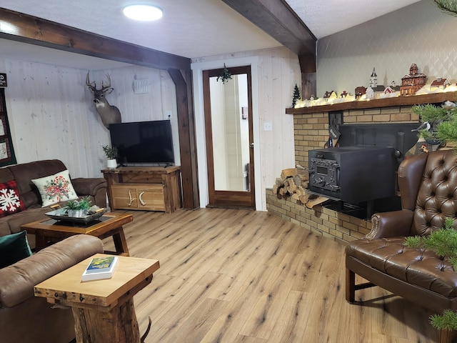 living room featuring beamed ceiling, light wood-type flooring, a wood stove, and an inviting chandelier