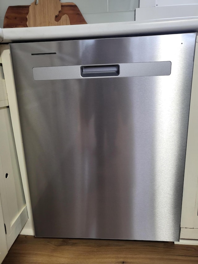 details with stainless steel dishwasher and dark hardwood / wood-style flooring