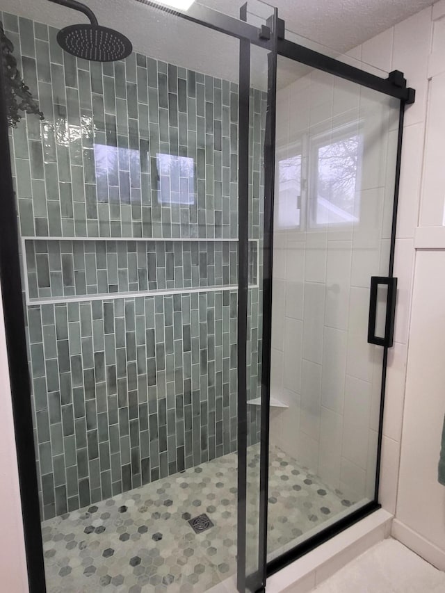 bathroom featuring a shower with shower door and a textured ceiling