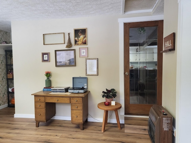 office space featuring heating unit, a textured ceiling, and light wood-type flooring