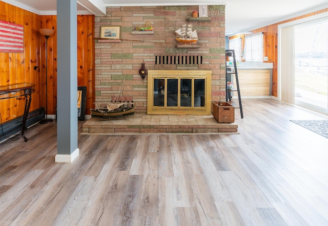 living room with a large fireplace, wooden walls, crown molding, and hardwood / wood-style flooring