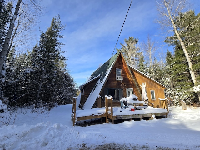 snow covered back of property with a wooden deck