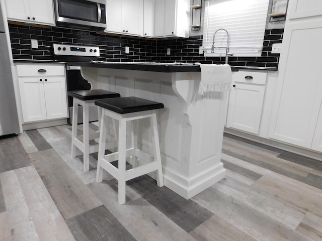 kitchen featuring white cabinets, a kitchen bar, and stainless steel appliances