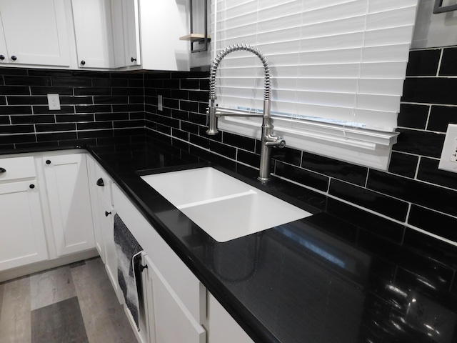 kitchen featuring decorative backsplash, white cabinetry, sink, and light wood-type flooring