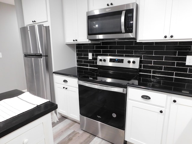 kitchen with decorative backsplash, white cabinetry, stainless steel appliances, and light wood-type flooring