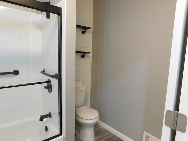 bathroom with wood-type flooring, toilet, and enclosed tub / shower combo