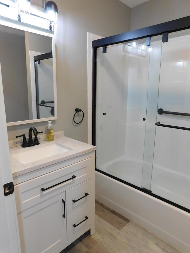 bathroom featuring hardwood / wood-style flooring, vanity, and combined bath / shower with glass door