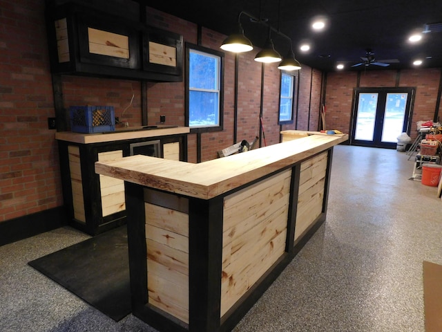 bar featuring light brown cabinets, ceiling fan, decorative light fixtures, butcher block counters, and brick wall