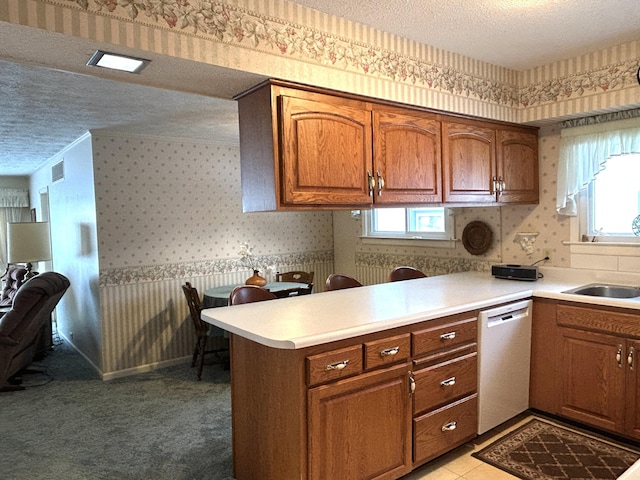 kitchen with plenty of natural light, light carpet, dishwasher, and a textured ceiling