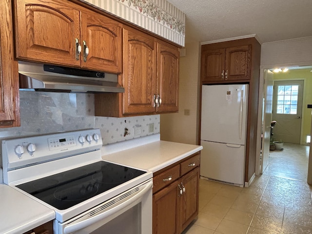 kitchen with a textured ceiling, decorative backsplash, and white appliances