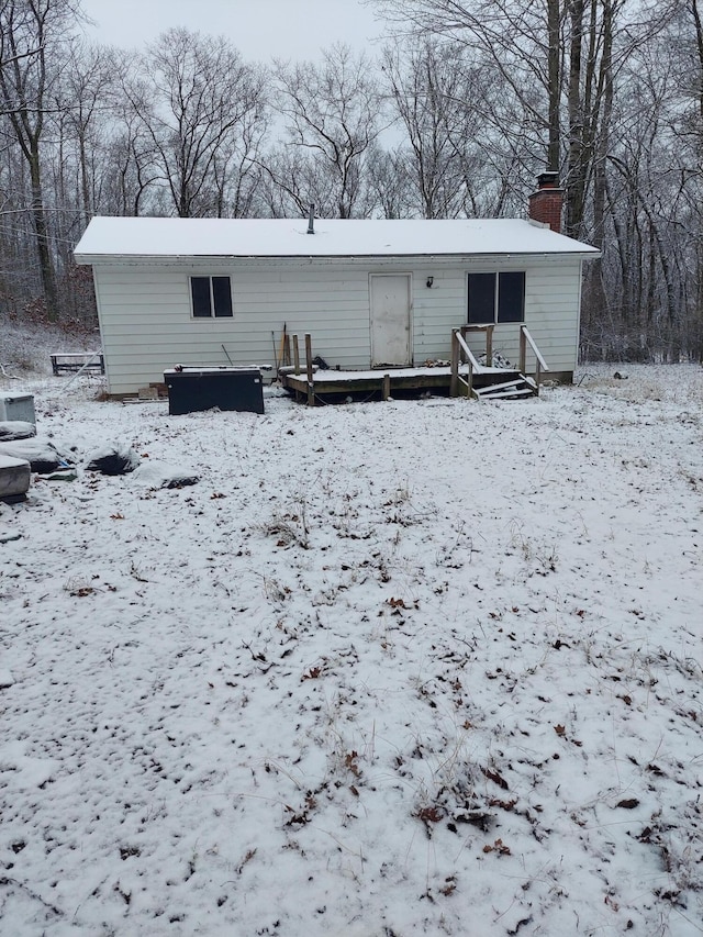 snow covered rear of property with a wooden deck