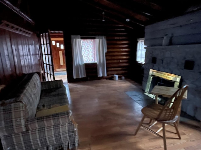 living room with hardwood / wood-style floors, beam ceiling, rustic walls, and a fireplace