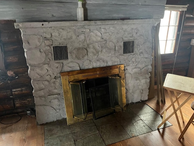 room details featuring a stone fireplace and wood-type flooring