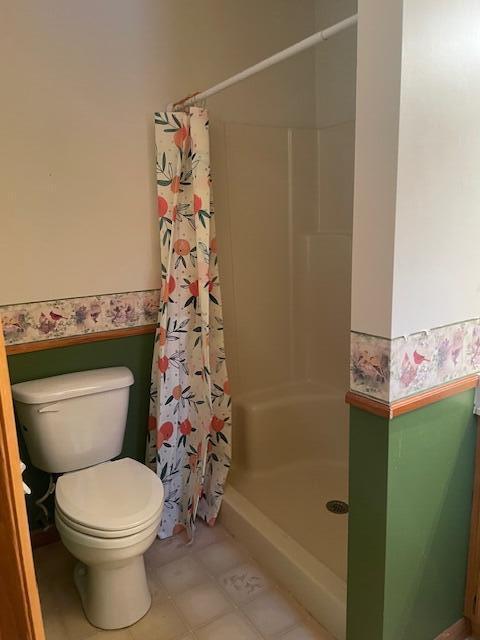 bathroom featuring a shower with curtain, tile patterned flooring, and toilet