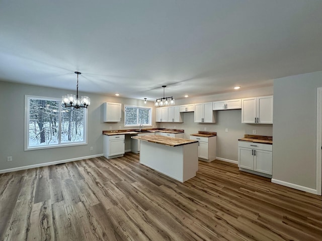 kitchen featuring white cabinets, a center island, butcher block countertops, and decorative light fixtures