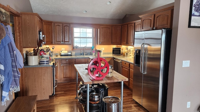 kitchen featuring appliances with stainless steel finishes, dark wood-style flooring, light countertops, and a sink