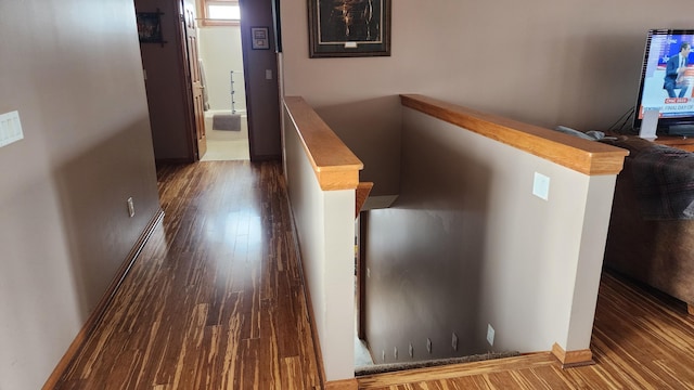 corridor featuring baseboards and wood finished floors