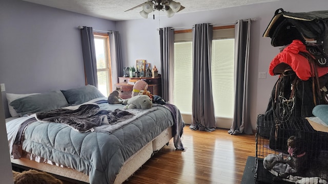 bedroom with a ceiling fan, a textured ceiling, and hardwood / wood-style flooring