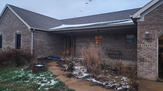 view of side of home with a shingled roof and brick siding