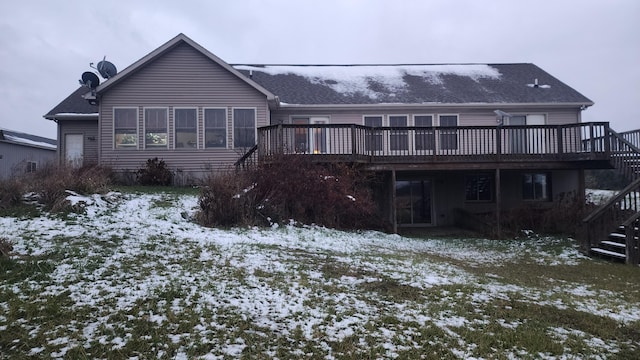 snow covered house with stairway and a wooden deck