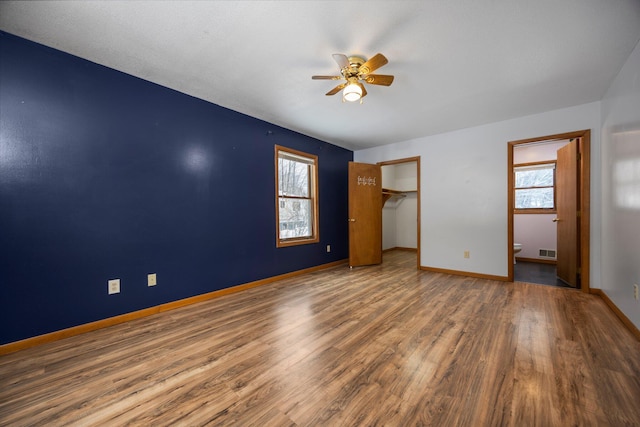 unfurnished bedroom featuring ceiling fan, a closet, wood-type flooring, and multiple windows