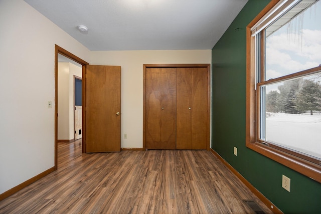 unfurnished bedroom with dark hardwood / wood-style flooring and a closet