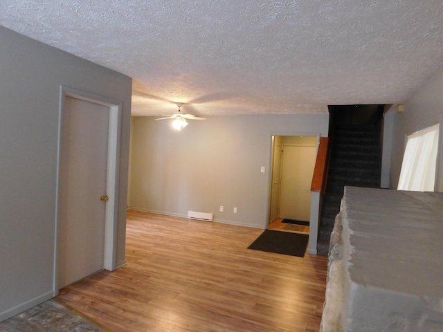 unfurnished living room with ceiling fan, light hardwood / wood-style flooring, and a textured ceiling