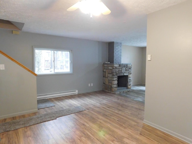 unfurnished living room with light wood-type flooring, a textured ceiling, baseboard heating, ceiling fan, and a fireplace