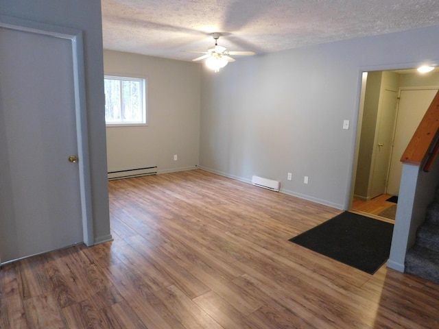 spare room featuring a textured ceiling, ceiling fan, baseboard heating, and hardwood / wood-style flooring