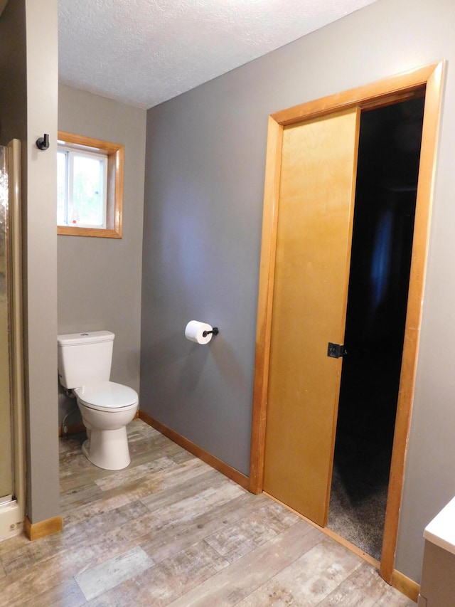 bathroom featuring a shower, wood-type flooring, a textured ceiling, and toilet