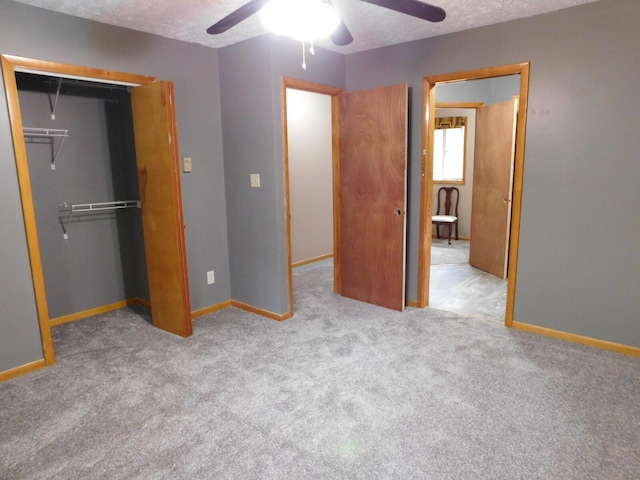 unfurnished bedroom featuring light carpet, a textured ceiling, a closet, and ceiling fan