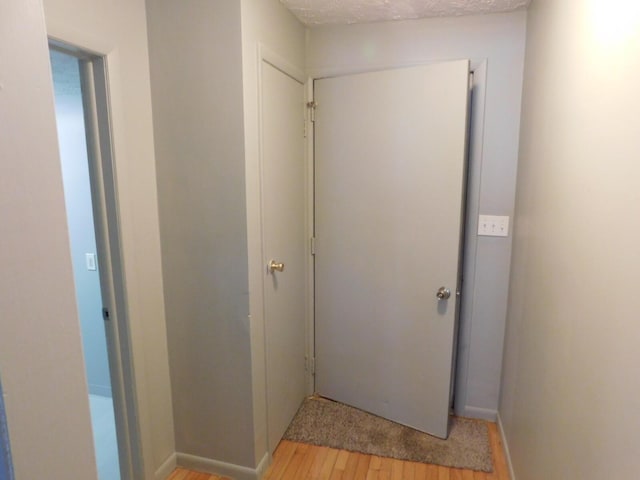 hallway featuring light hardwood / wood-style floors and a textured ceiling