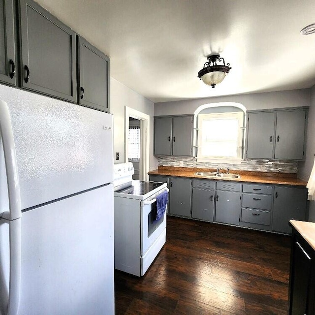 kitchen featuring decorative backsplash, gray cabinetry, white appliances, sink, and dark hardwood / wood-style floors