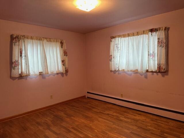 spare room with hardwood / wood-style floors and a baseboard heating unit