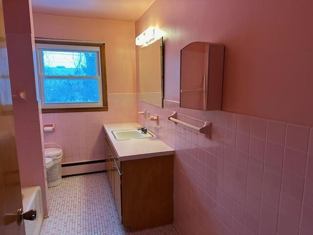 bathroom with tile patterned flooring, vanity, a baseboard radiator, and tile walls