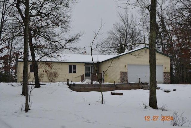 snow covered rear of property featuring a garage