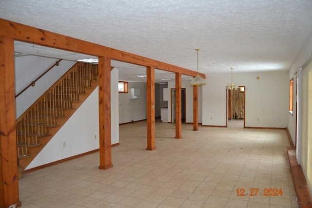 basement featuring a textured ceiling and an inviting chandelier