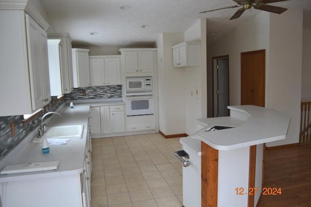 kitchen featuring decorative backsplash, white appliances, a kitchen island, sink, and white cabinetry