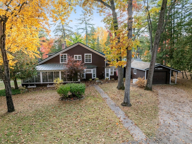 view of front of house featuring a sunroom, a garage, and an outdoor structure