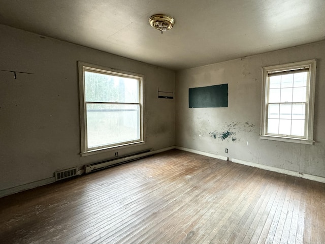 spare room featuring hardwood / wood-style floors, a baseboard radiator, and a wealth of natural light